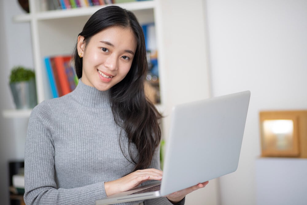 A smiling woman holding a laptop