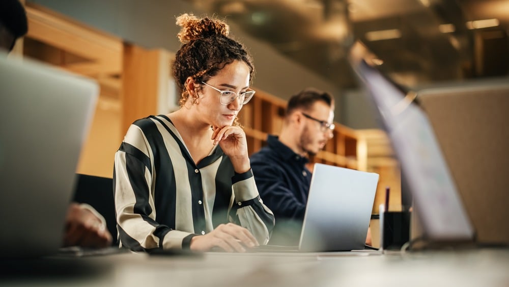 A woman in an office working on a laptop