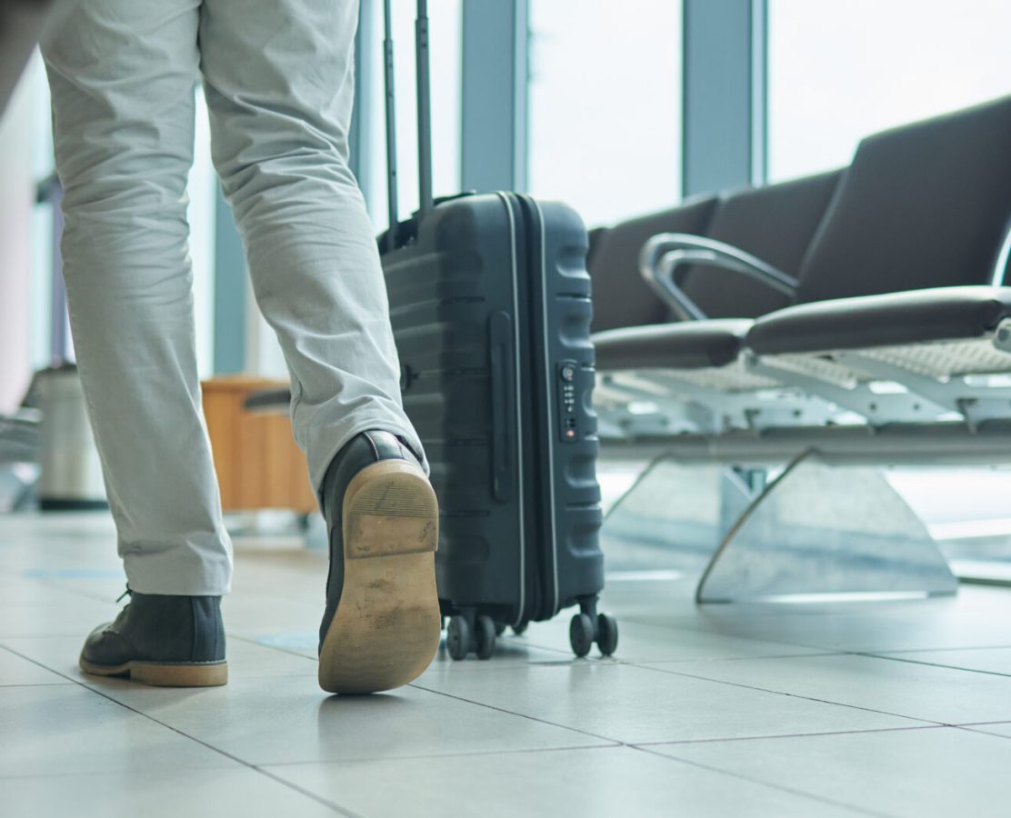 Airport, suitcase and person legs walking to flight for international opportunity or global journey in lobby. Luggage of entrepreneur or business man feet with vacation, travel agency or hospitality.